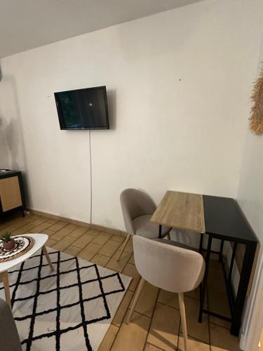 ein Wohnzimmer mit einem Tisch und einem TV an der Wand in der Unterkunft Charmant t1 dans le verdon in Gréoux-les-Bains