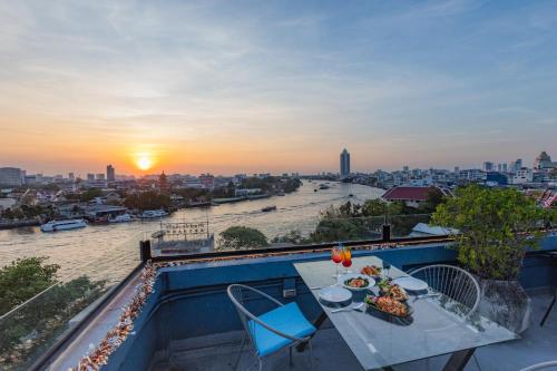 a table and chairs on a balcony with a view of a river at River View Residence in Bangkok