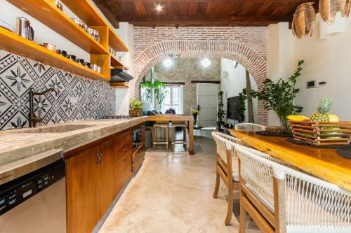 a kitchen with a counter with chairs and a table at Casa Coco 1680 Colonial & Art House In Old City - Pool - Jasussi - View in Cartagena de Indias