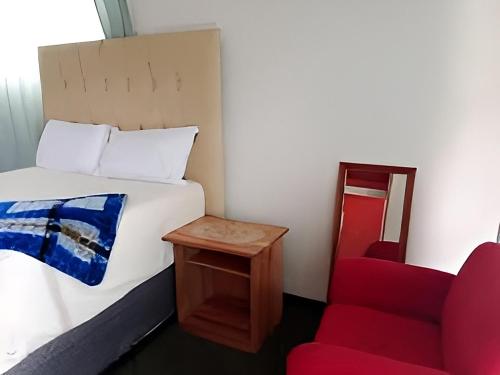 ein Schlafzimmer mit einem Bett und einem roten Stuhl in der Unterkunft Run n Fire in Mbabane
