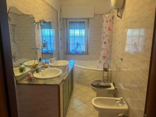 a bathroom with two sinks and a tub and a toilet at Casa Sophie in Oristano