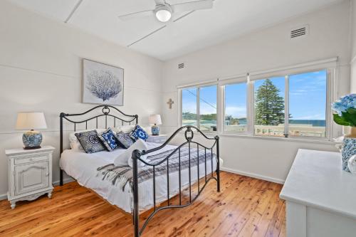a bedroom with a bed and two windows at Delightful 3-Bed Home Minutes from Avoca Beach in Avoca Beach