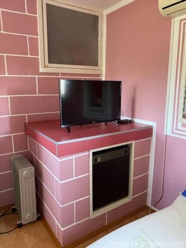 Una pared de ladrillo rosa con una TV encima. en Kuća na Drini, en Luke