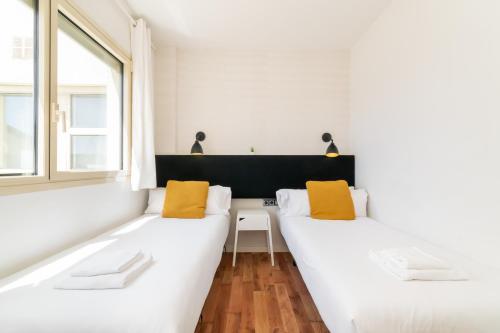 two white beds in a room with a window at Unique Rentals - Placa Catalunya Central Apartments in Barcelona