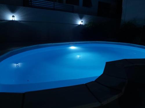 uma piscina iluminada à noite com luzes azuis em Yuti Homestay em Quatre Bornes