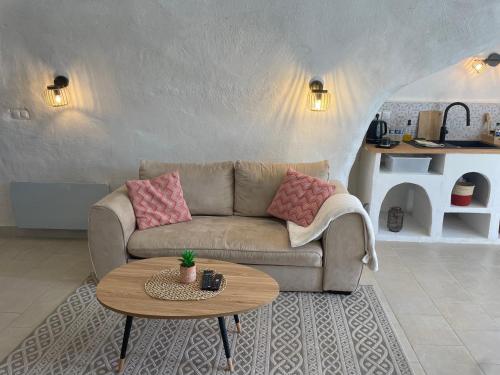 een woonkamer met een bank en een tafel bij Logement troglodyte tout confort 42 min tgv Paris in Naveil
