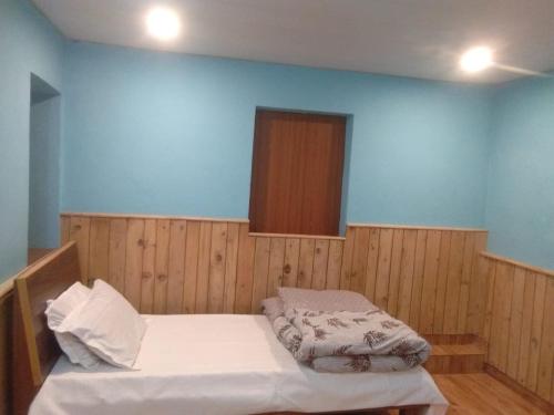 Cama en habitación con pared azul en DS Residency Homestay, Mohana, en Chakrāta