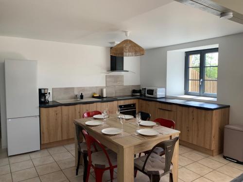une cuisine avec une table en bois et des chaises ainsi qu'une salle à manger dans l'établissement COTTAGES LA CHENERIE, à Ancteville