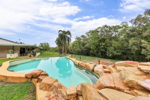 a swimming pool with a rock wall around it at Riverside Homestead in Southport
