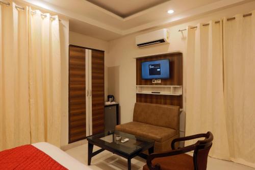 a bedroom with a chair and a tv in a room at GREEN LOTUS SAI INTERNATIONAL in New Delhi