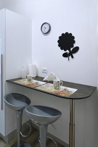 a kitchen with two stools and a counter with a clock at House of the Twins in Mesagne
