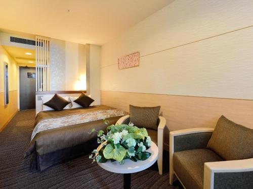 pokój hotelowy z łóżkiem i stołem z kwiatami w obiekcie Heian No Mori Kyoto w mieście Kioto