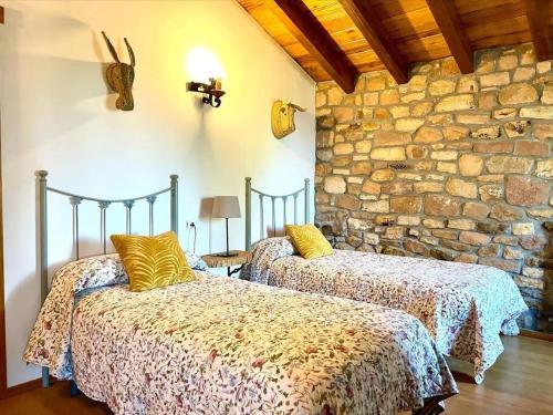 2 camas en una habitación con una pared de piedra en El currillo preciosa casa rural al lado cabarceno, en Argomilla