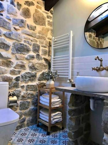 a bathroom with a sink and a stone wall at La Fontana, descubre Cabarceno y Cantabria in Villacarriedo