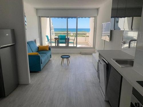 un salon avec un canapé bleu et une table dans l'établissement Vittoria Immobilier-375-Vue mer- REGLEMENT SUR PLACE -Chèques Vacances acceptés, à La Grande Motte