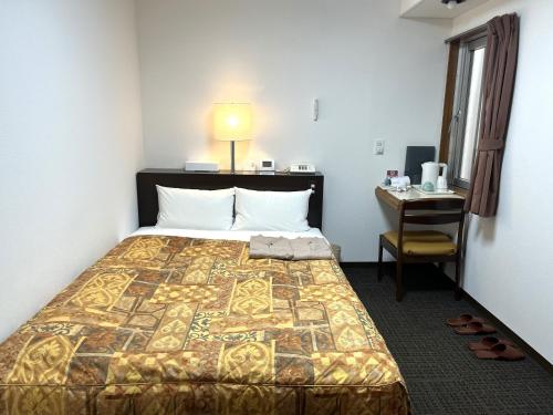 ein Hotelzimmer mit einem Bett, einem Schreibtisch und einem Tisch in der Unterkunft Hotel Tokeidai in Sapporo