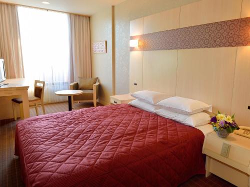 um quarto de hotel com uma cama grande e um cobertor vermelho em Heian No Mori Kyoto em Quioto