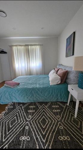 1 dormitorio con 1 cama grande y 1 alfombra en Rare GEM in Westgate en Auckland