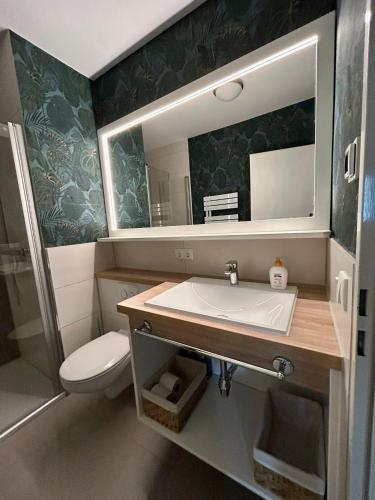 a bathroom with a sink and a toilet and a mirror at Ferienwohnung „mittendrin“ in Zinnowitz