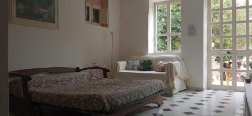 a bedroom with a bed and a chair and windows at Il giardino di Emilia in Raviscanina