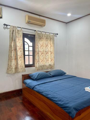 Saysouly Guest House في Ban Nongdouang: غرفة نوم بسرير وملاءات زرقاء ونافذة