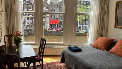 um quarto com uma cama, uma mesa e janelas em Canal View B&B Amsterdam em Amsterdã