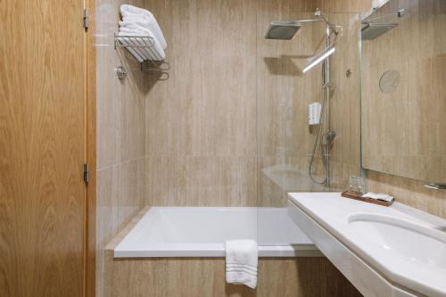 a bathroom with a sink and a mirror and a shower at Alva Valley Hotel in Oliveira do Hospital