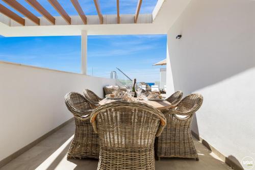 una sala da pranzo con tavolo e sedie in vimini di Penthouse Diamond - Private Pool, Terrace, Sea View, Gym & BBQ a Las Lagunas Mijas
