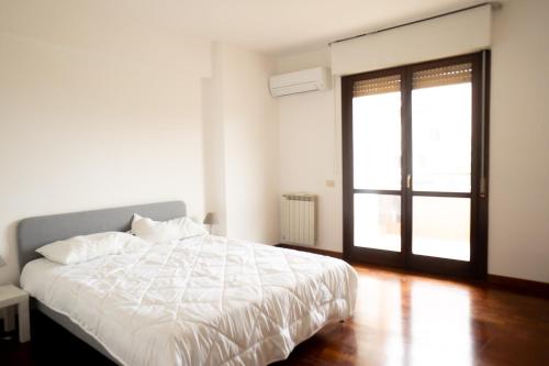 a bedroom with a white bed and a window at Ermete Eur House in Rome