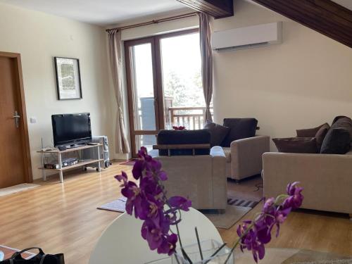 a living room with a couch and a table with purple flowers at Cozy Mountain Apartment in Borovets