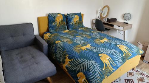 1 cama con edredón azul y dorado y silla en Villa des Roses : Maison 3 chambres au calme, 7 pers, wifi, en Le Havre