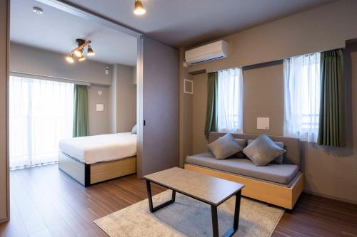 a bedroom with a bed and a couch and a table at ALTERNA Kuramae in Tokyo