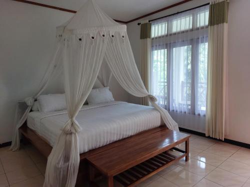 a bedroom with a canopy bed with a wooden table at Hôtel La Belle Etoile in Labuan Bajo