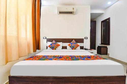 Schlafzimmer mit einem großen weißen Bett und orangefarbenen Vorhängen in der Unterkunft FabHotel KRB Paradise in Dehradun