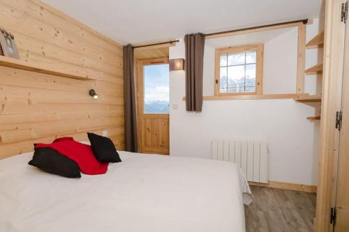 een slaapkamer met een wit bed en een raam bij Chalet Epilobe - pied des pistes - vue magnifique in Montvalezan