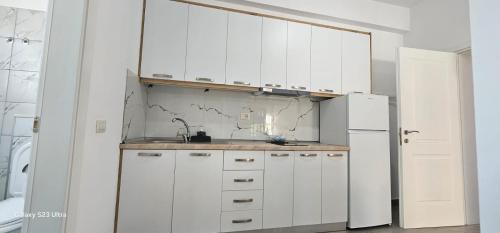 a white kitchen with a sink and a refrigerator at Ambla Apartaments Orikum in Orikum