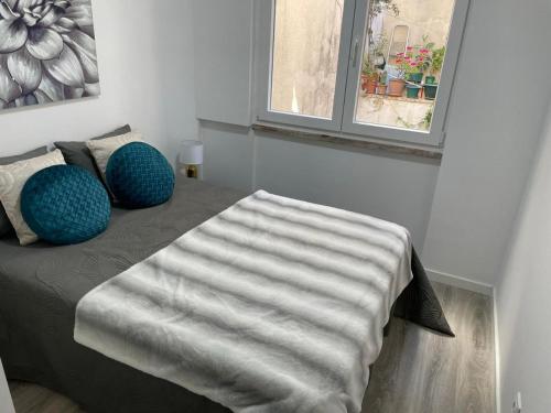 a bedroom with a bed with blue pillows and a window at Mentor Molly in Amadora