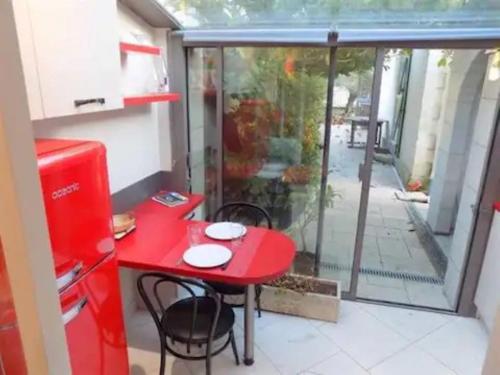 - une table et des chaises rouges dans une chambre avec fenêtre dans l'établissement Studio maisonnette 200 m de la plage tout à pieds, à Saint-Palais-sur-Mer