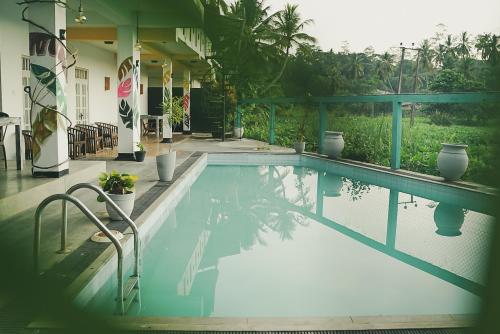 a swimming pool in front of a house at Leyon Paradise Hotel in Unawatuna