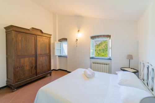 1 dormitorio con 2 camas y armario de madera en La Casetta del Casale In Vigna, CinqueTerreCoast, en Casarza Ligure