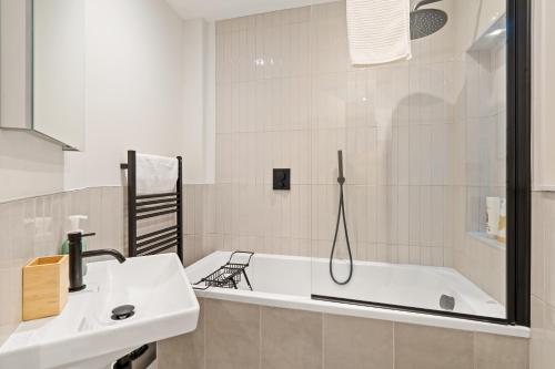 La salle de bains blanche est pourvue d'une baignoire et d'un lavabo. dans l'établissement Central Richmond 3 Bedroom House, à Richmond upon Thames