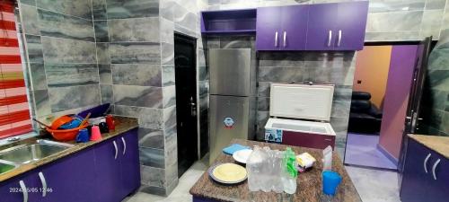 uma pequena cozinha com armários roxos e um balcão em THE MARBLE ARCH em Uyo