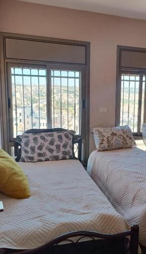 1 Schlafzimmer mit 2 Betten und 2 Fenstern in der Unterkunft Abram's appartment in the Center of Bethlehem city in Bethlehem