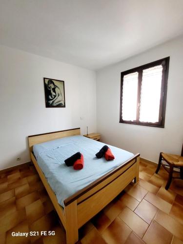 une chambre avec un lit avec deux oreillers rouges dessus dans l'établissement T2 bord de mer Agosta, à Albitreccia