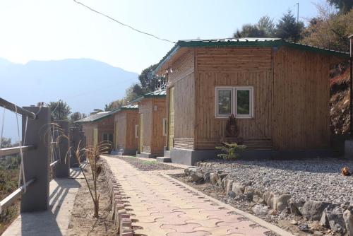 a row of small wooden buildings with a sidewalk at Basera Home stay in Gopeshwar
