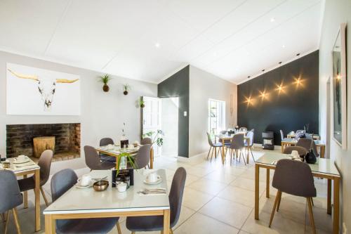 a living room with tables and chairs and a fireplace at El Dorado Hotel and Self Catering in Oudtshoorn