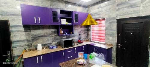 eine Küche mit lila Schränken und einer gelben Lampe in der Unterkunft THE MARBLE ARCH in Uyo