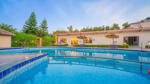 una piscina frente a una casa en Corbett Fun Resort en Rāmnagar