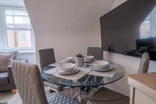 uma sala de jantar com uma mesa de vidro e cadeiras em Peterhead Stay - SJA Stays - Modern 2 Bed Apartment em Peterhead