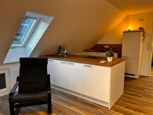 an attic kitchen with a counter and a chair at Ferienwohnung im Resi Gesundheitszentrum in Freudenberg